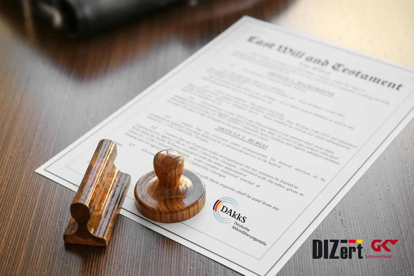 Holzstempel mit einem abgerundeten Griff und einer flachen Basis, auf dessen Oberfläche das DAKkS-Logo graviert ist.